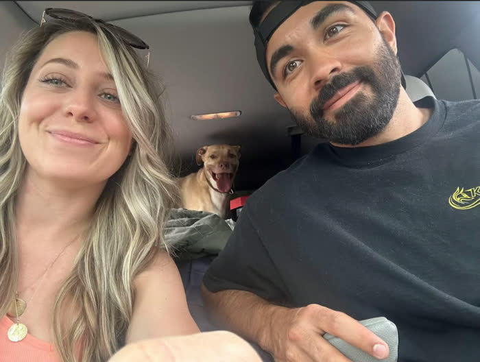Smiling road-trip selfie in the car with one of the dogs in the back seat